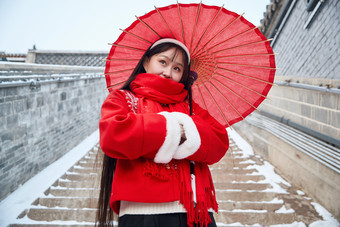 雪后在老城古巷穿着喜庆服饰的亚洲少女