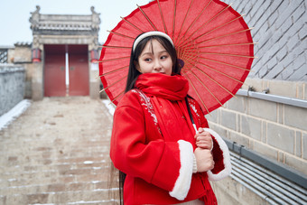 雪后在老城古巷穿着喜庆服饰的亚洲少女