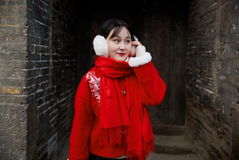 雪后在老城古巷穿着喜庆服饰的亚洲少女