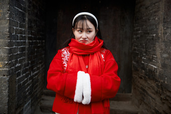 雪后在老城古巷穿着喜庆服饰的亚洲少女