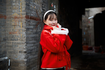 雪后在老城古巷穿着喜庆服饰的亚洲少女