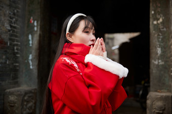 雪后在老城古巷穿着喜庆服饰的亚洲少女