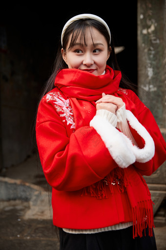 雪后在老城古巷穿着喜庆服饰的亚洲少女