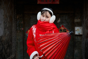 雪后在老城古巷穿着喜庆服饰的亚洲少女