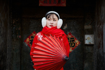 雪后在老城古巷穿着喜庆服饰的亚洲少女