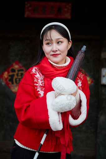 雪后在老城古巷穿着喜庆服饰的亚洲少女