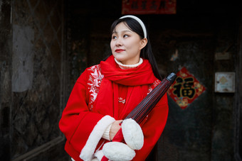 雪后在老城古巷穿着喜庆服饰的亚洲少女