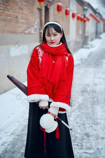 雪后在老城古巷穿着喜庆服饰的亚洲少女