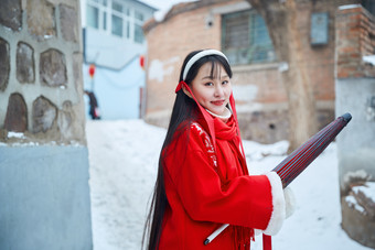 雪后在老城古巷穿着喜庆服饰的亚洲少女