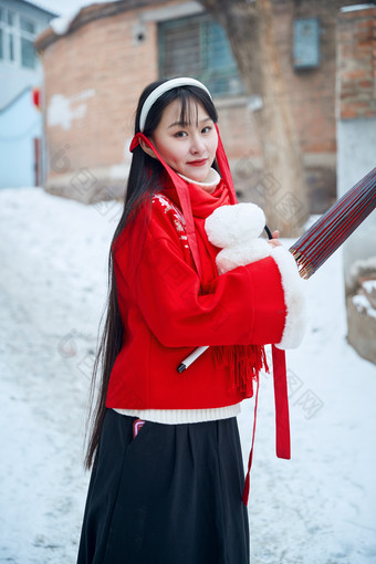 雪后在老城古巷穿着喜庆服饰的亚洲少女