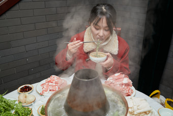 在饭店吃传统铜锅涮肉的亚洲少女