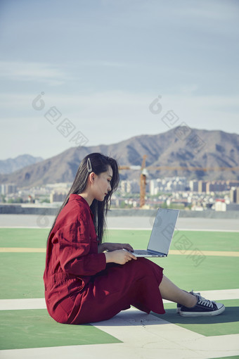 亚洲商务年轻女性在楼顶停机坪使用电脑办公