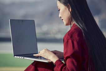 亚洲商务年轻<strong>女性</strong>在楼顶停机坪使用电脑办公