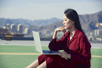 亚洲商务年轻<strong>女性</strong>在楼顶停机坪使用电脑办公