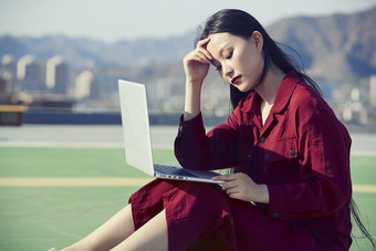 亚洲商务年轻<strong>女性</strong>在楼顶停机坪使用电脑办公