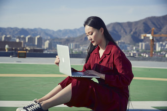 亚洲商务年轻<strong>女性</strong>在楼顶停机坪使用电脑办公