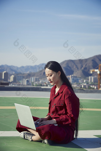 亚洲商务年轻女性在楼顶停机坪使用电脑办公