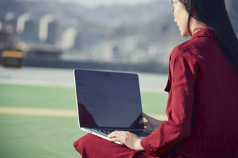 亚洲商务年轻女性在楼顶停机坪使用电脑办公