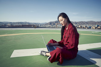 亚洲商务年轻<strong>女性</strong>在楼顶停机坪使用电脑办公