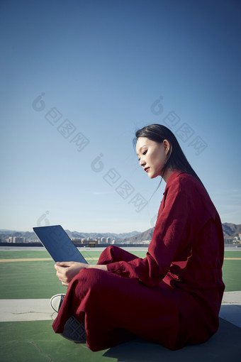 亚洲商务年轻女性在楼顶停机坪使用电脑办公