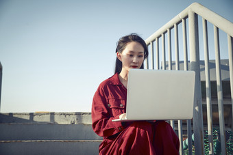 亚洲商务年轻女性在楼顶停机坪使用电脑办公