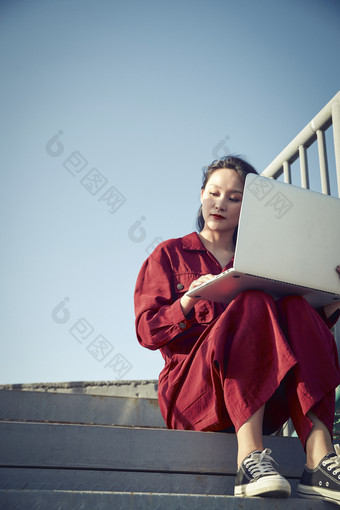 亚洲商务年轻女性在楼顶停机坪使用电脑办公