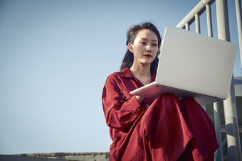 亚洲商务年轻<strong>女性</strong>在楼顶停机坪使用电脑办公