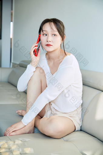 在沙发<strong>床上玩手机</strong>的年轻亚洲女性