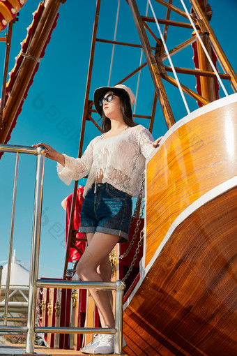 站在游乐场海盗船旁边的美女