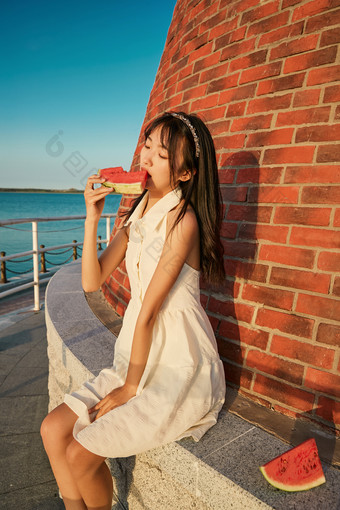 <strong>盛夏</strong>夕阳湖边码头灯塔上吃西瓜的少女