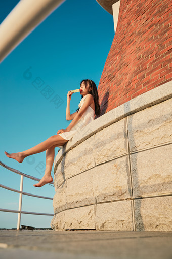 盛夏夕阳湖边码头灯塔上吃西瓜的少女