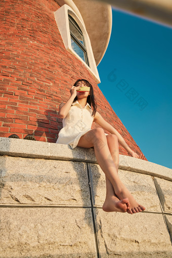 盛夏夕阳湖边码头灯塔上吃西瓜的少女