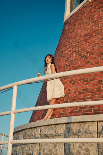 盛夏夕阳湖边码头灯塔上吃西瓜的少女