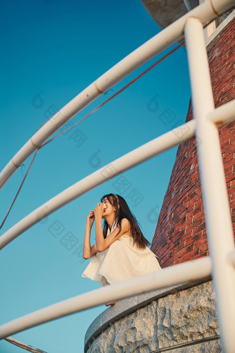 <strong>盛夏</strong>夕阳湖边码头灯塔上吃西瓜的少女