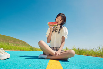 夏日户外湖边彩色公路上玩耍吃西瓜的少女