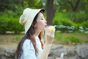户外公园里玩吹泡泡的可爱亚洲少女