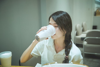 在烘焙店吃面包喝牛奶的可爱亚洲少女