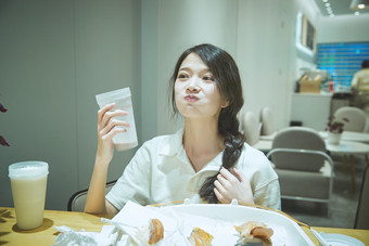 在烘焙店吃面包喝牛奶的可爱亚洲少女