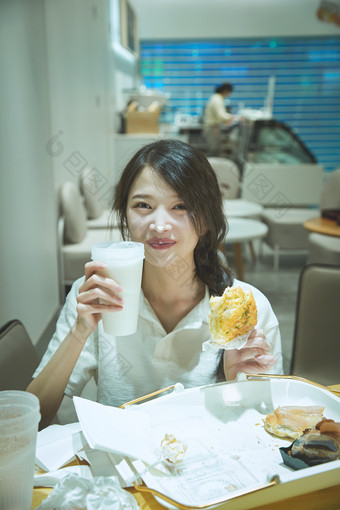 在烘焙店吃面包喝牛奶的可爱亚洲少女