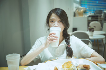 在烘焙店吃面包喝牛奶的可爱亚洲少女