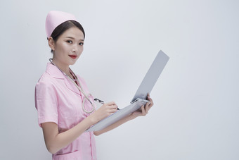 穿粉色护士服戴<strong>听诊器手持</strong>病历夹的医护人员