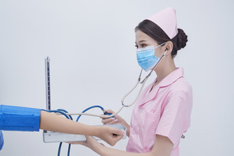 手拿血压测量仪为患者诊治量血压的女性护士