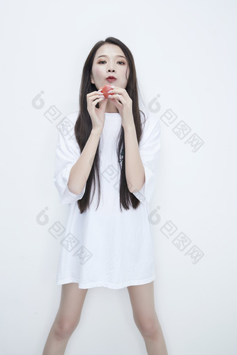 吃番茄的身穿白色长T血衬衫的长发少女人像
