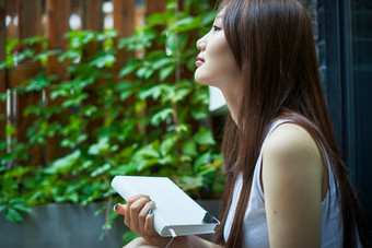 院子里坐在长椅上阅读书籍的<strong>亚洲长发</strong>少女