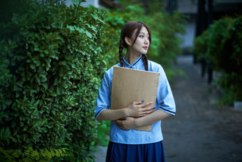 细雨中庭院里竹林前怀抱古书籍的民国风少女