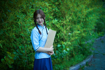 细雨中庭院里竹林前怀抱古书籍的<strong>民国风</strong>少女