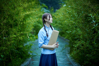 细雨中庭院里竹林前怀抱古书籍的<strong>民国</strong>风少女