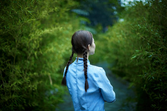 细雨中庭院里竹林前怀抱古书籍的民国风少女