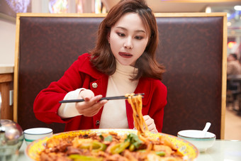 在餐厅吃美味新疆大盘鸡的亚洲少女