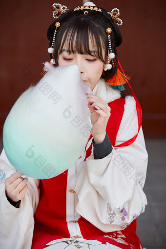 身穿喜庆汉服吃棉花糖的少女